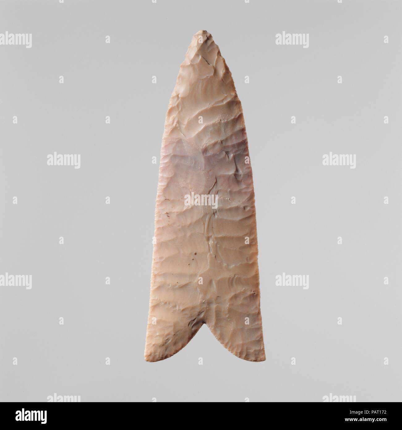 Flint Blade. Dimensions: L. 5.8 x 0.8 x 15.7 cm (2 5/16 x 5/16 x 6 3/16 in.). Date: ca. 3650-3300 B.C..  Blades such as this one were included in burials throughout the Predynastic Period.The cutting edge is the V-shaped notch. Although the implement's exact purpose is unknown, there is persua-sive evidence that it was used at birth to cut the umbilical cord and was placed in the grave to assist its owner's rebirth into the afterlife.  A similar instrument was used throughout Egyptian history in the funerary rite known as the 'Opening of the Mouth': touched to the mouth of the deceased's mumm Stock Photo
