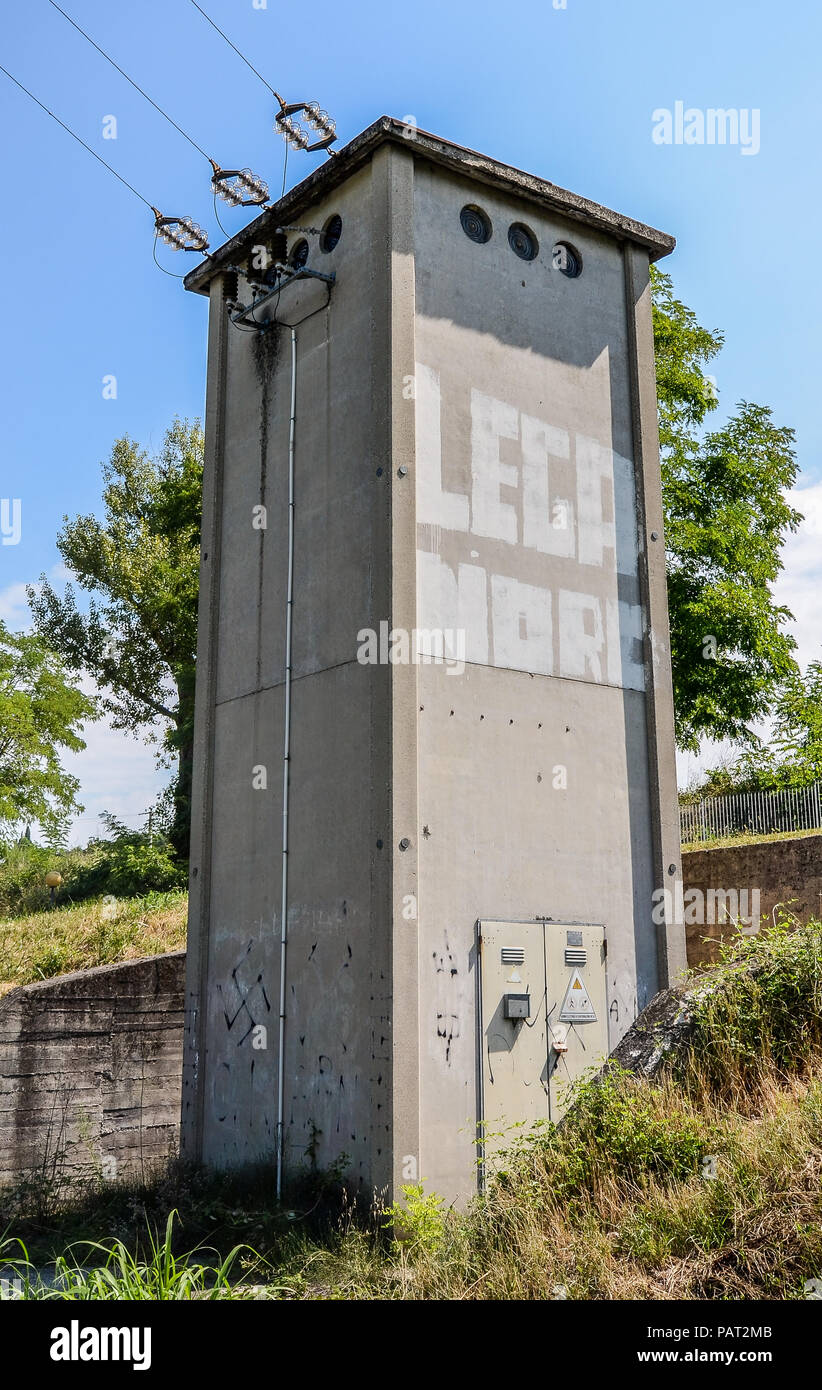 Graffiti written 'Lega Nord' on an electric tower on side of the road with Nazi Swastikas spray painted throughout the bottom Stock Photo