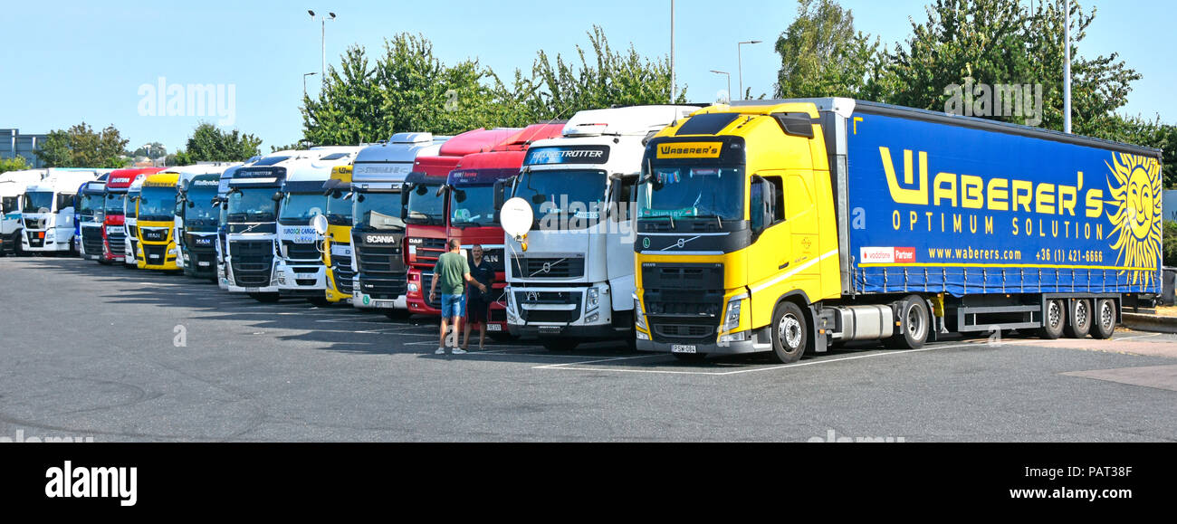 Foreign hgv lorry truck & trailers at overnight motorway parking on Thurrock services two driver talking cab TV satellite dish on trucks & lorries UK Stock Photo