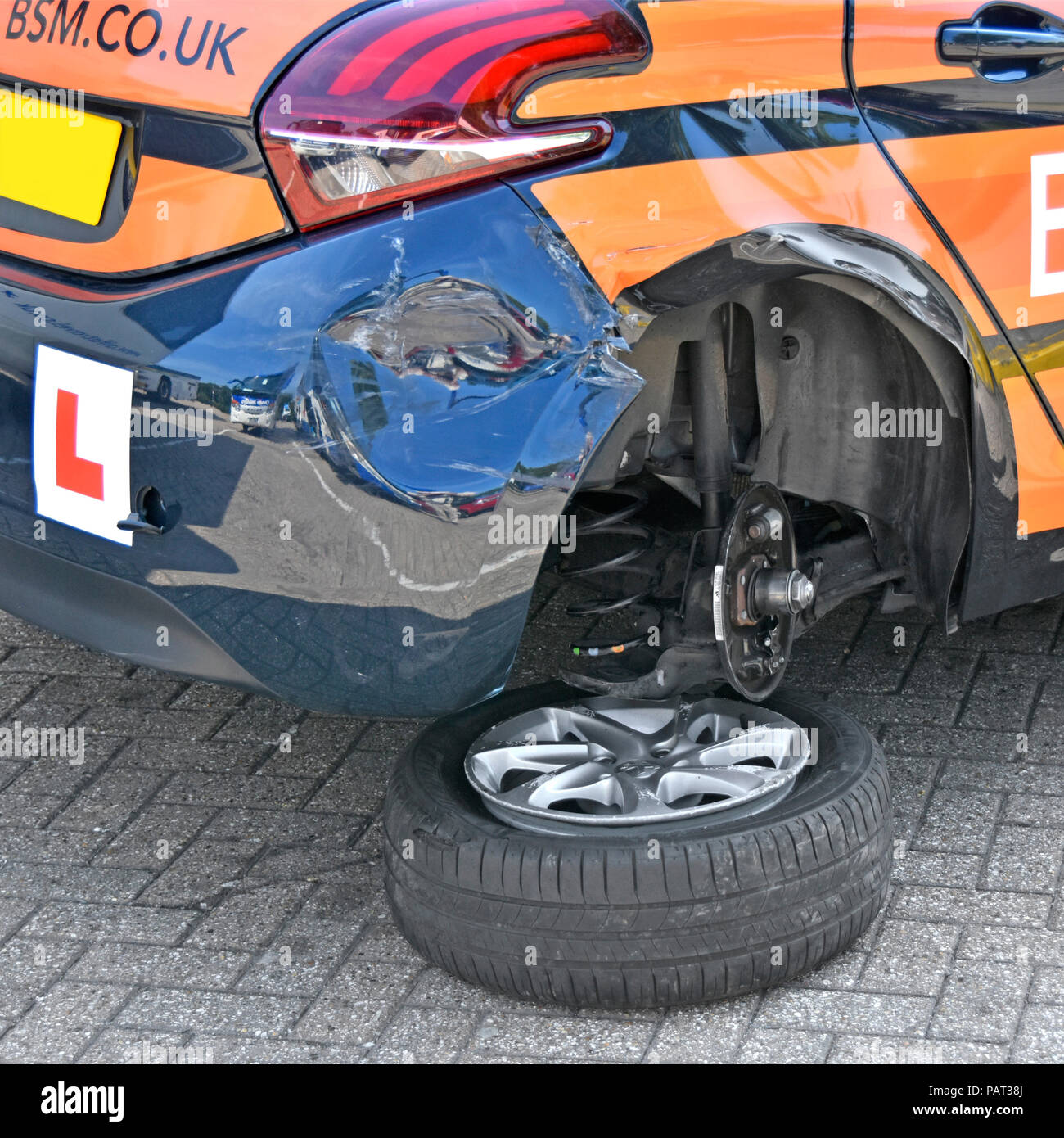 Rear wheel & tyre from L Plate hatchback car after crash accident damaged BSM learner driver driving school car parked in service area England UK Stock Photo