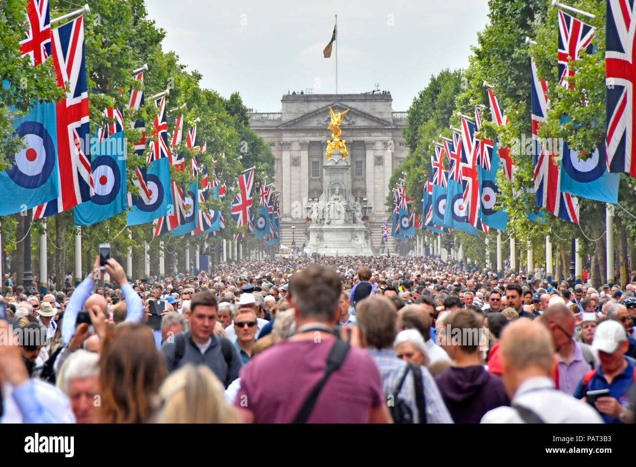 Crowds of people in The Mall London at Royal Air force RAF centenary street scene parade & flypast event Union Jack flags Buckingham Palace England UK Stock Photo