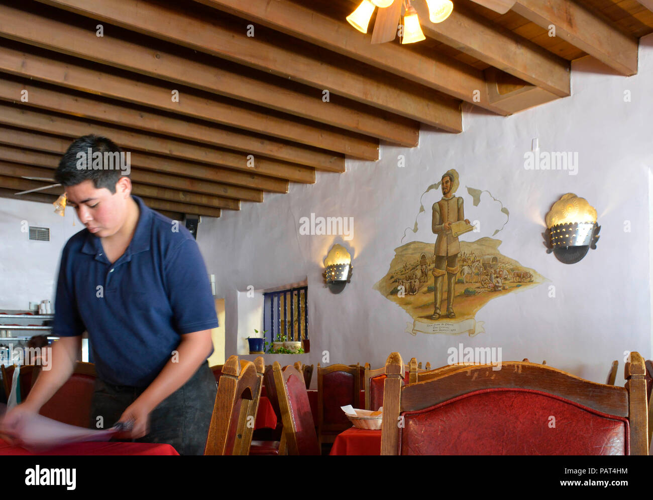 Waiter sets table inside the Oldest restaurant in old town Albuquerque, La Placita, with Spanish settlers honored with frescoes on walls Stock Photo