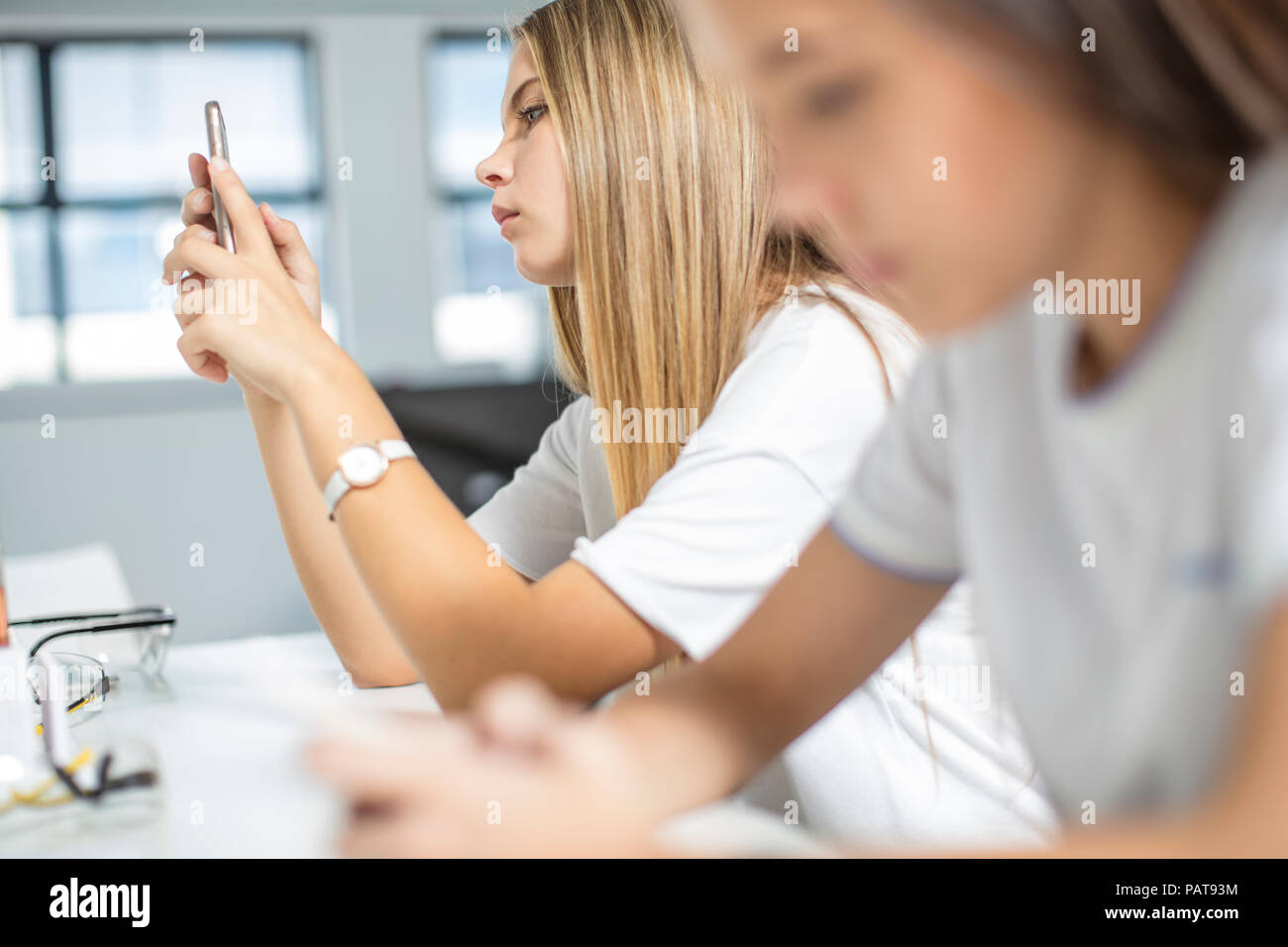 Teenage girls using cell phones in class Stock Photo