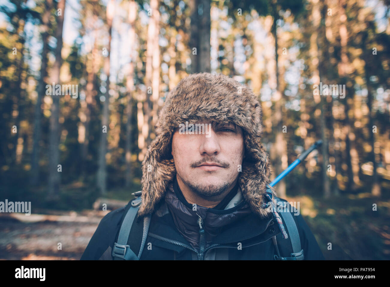 Sweden, Sodermanland, portrait of young man wearing fur cap in remote landscape Stock Photo