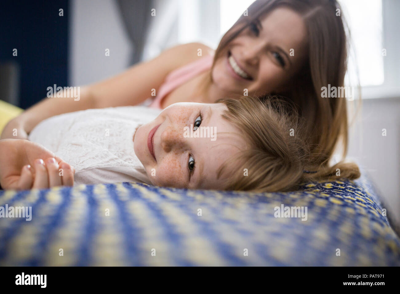 Happy mother and daughter lying on bed Stock Photo