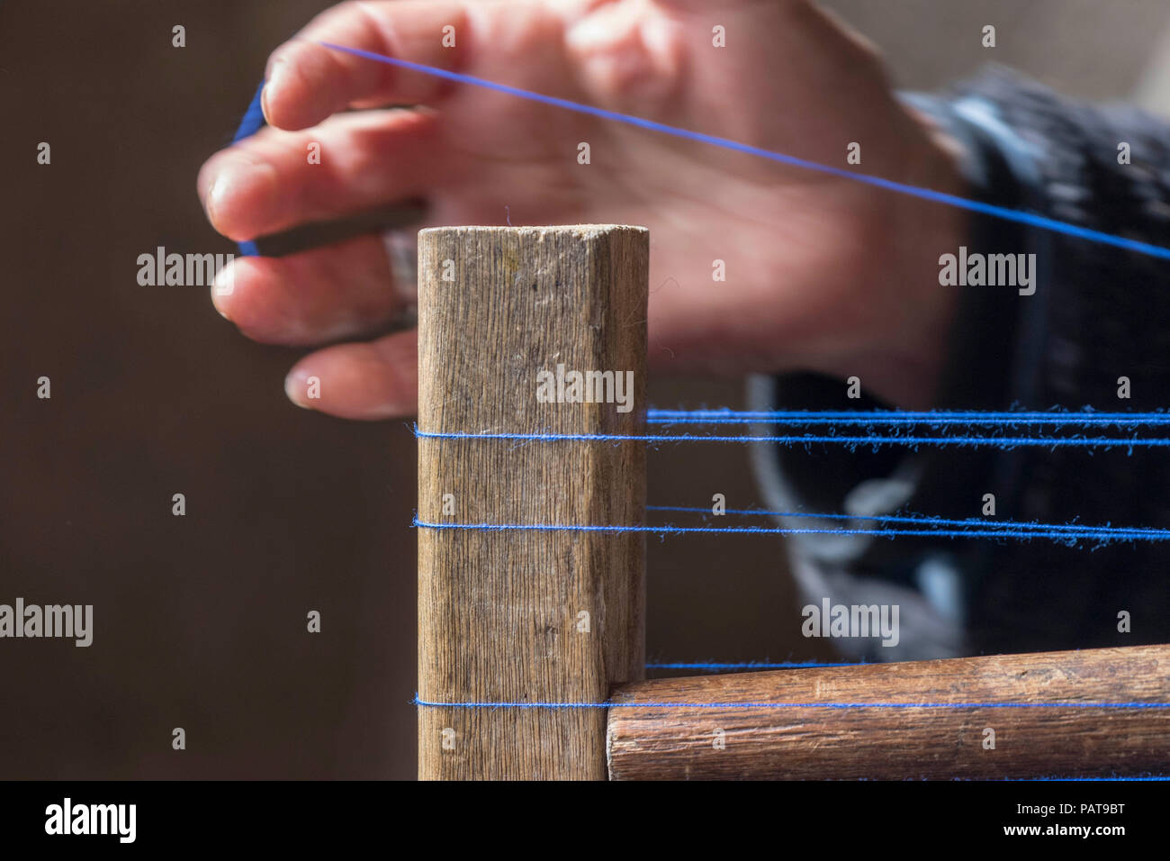 Thread on a loom with a hand in the background. Stock Photo