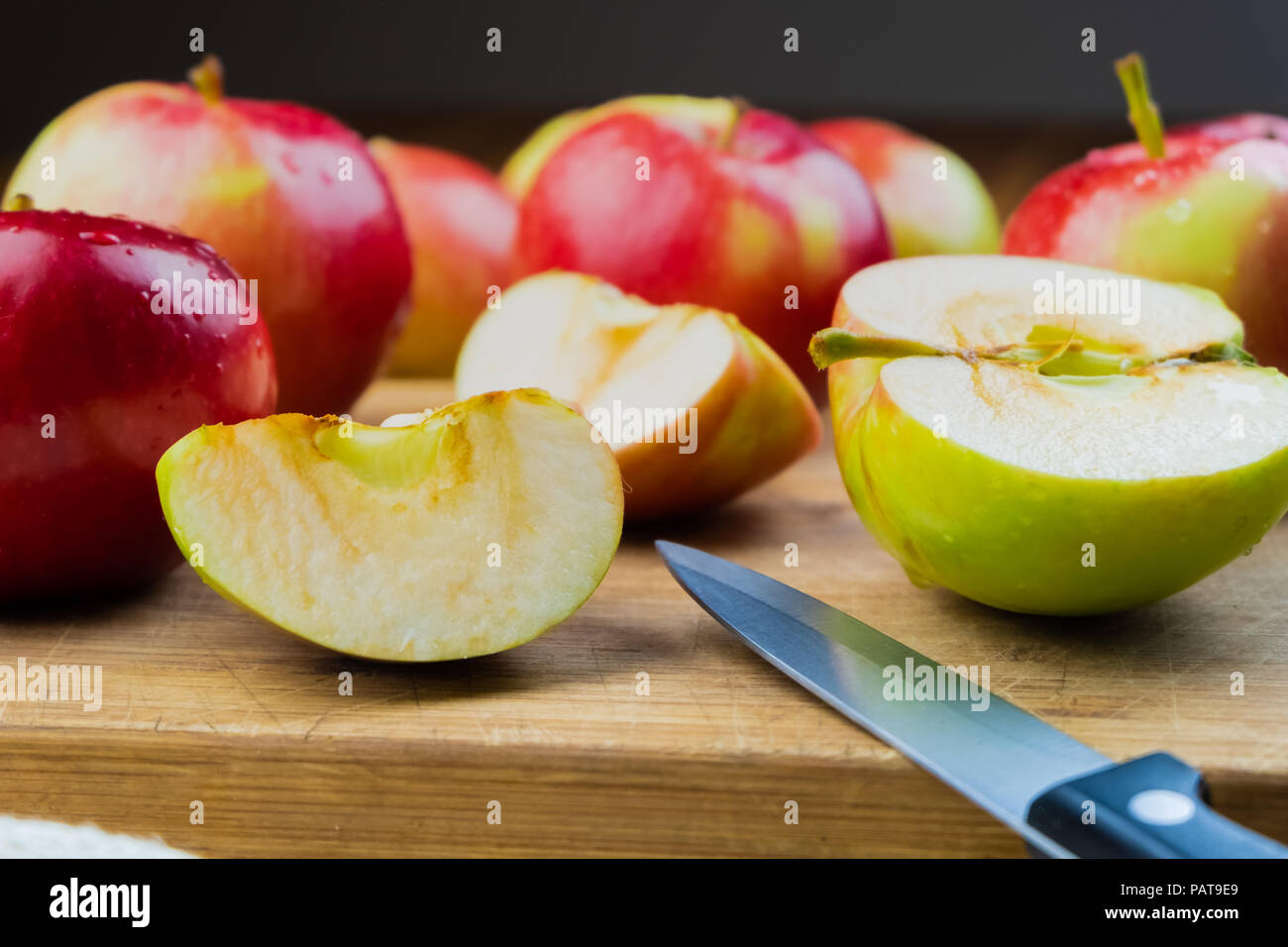 Close-up of ripe juicy apples on wooden table. Home grown organic apples and knife on rustic table background Stock Photo