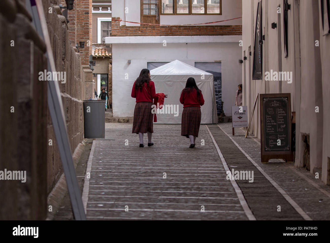 Two Catholic school girls in uniform walking in an alley in Ecuador Stock Photo