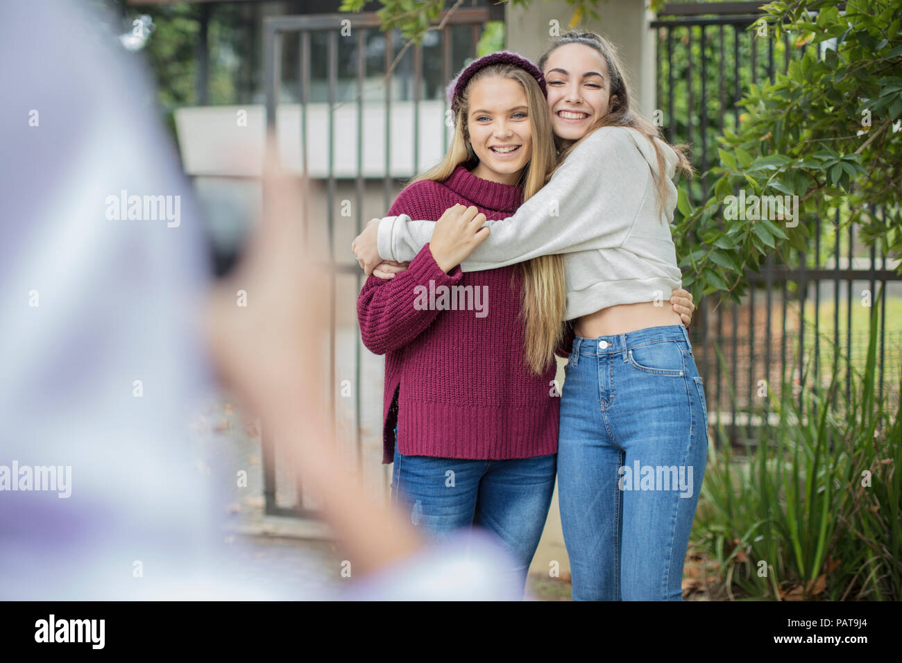 Teenage girl taking a picture of her happy friends outdoors Stock Photo