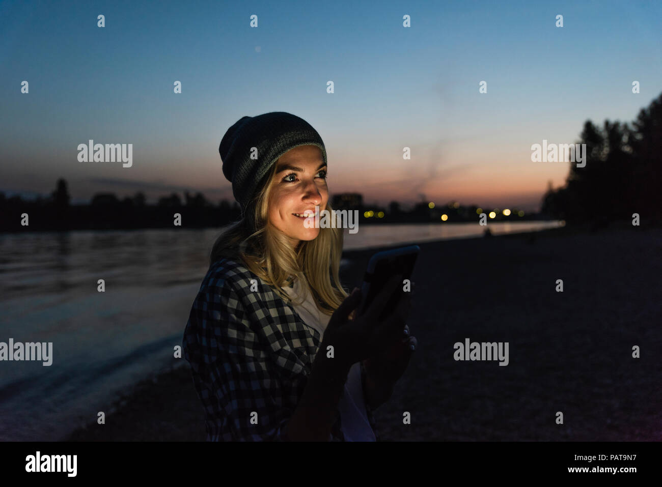 Young woman using smartphone on riverside in the evening Stock Photo