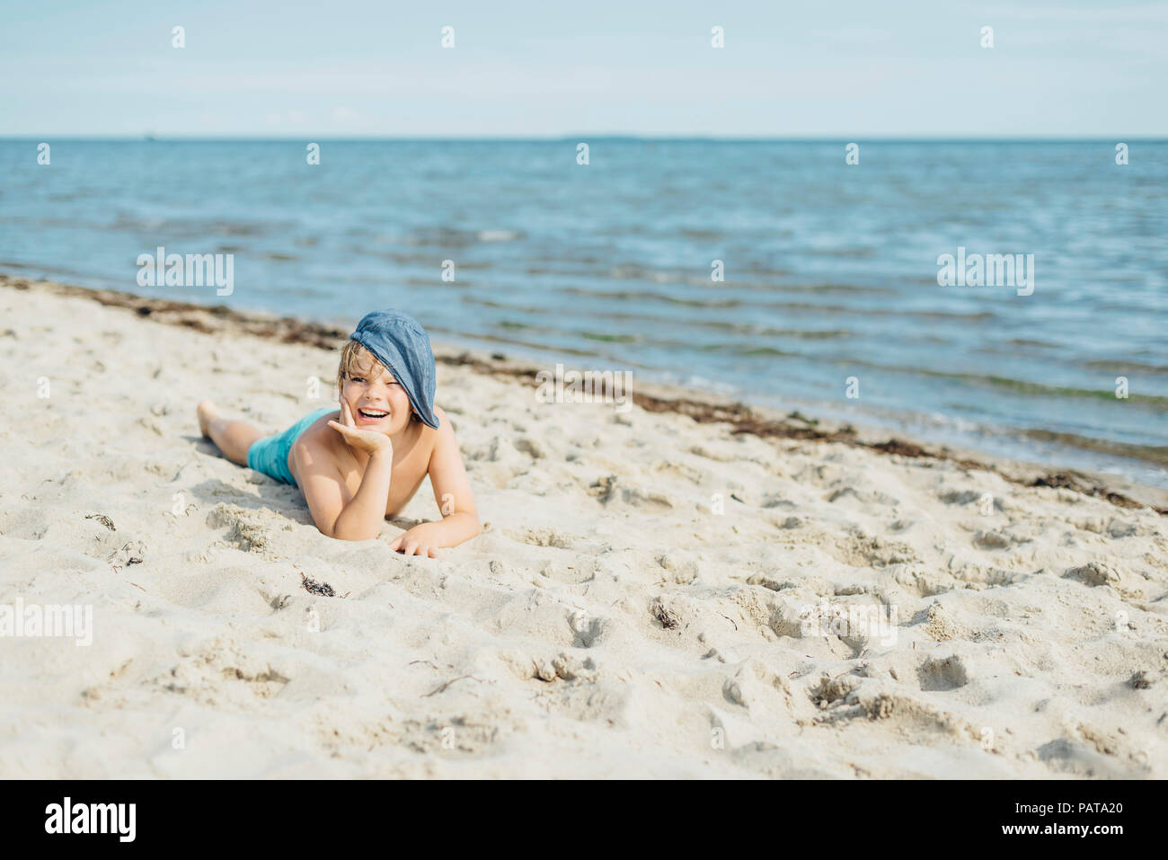 Portrait of happy boy lying on the beach Stock Photo