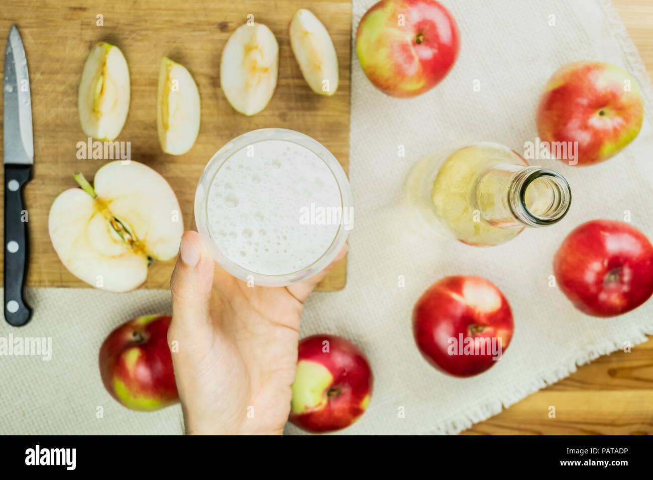 Flat lay with glass of sparkling cidre drink on rustic wooden table. Point of view of hand holding glass of home made cider and locally grown organic  Stock Photo