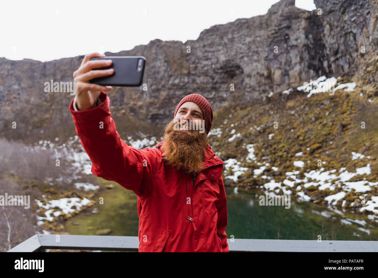 Iceland, smiling bearded man using smartphone, selfie Stock Photo