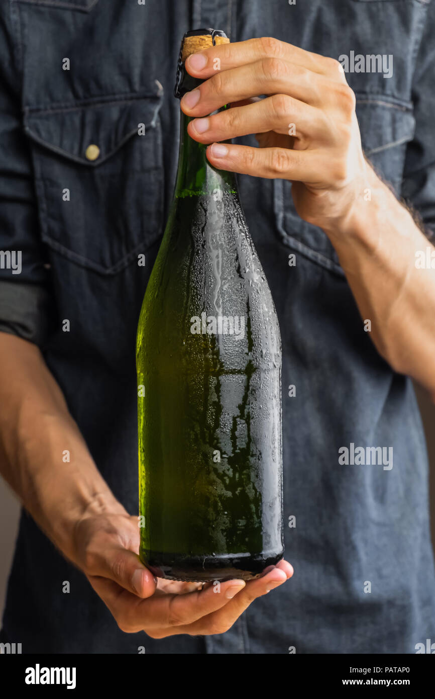 Male hands holding corked bottle of premium cidre. Beautiful ice cold bottle of apple wine in man's hands Stock Photo