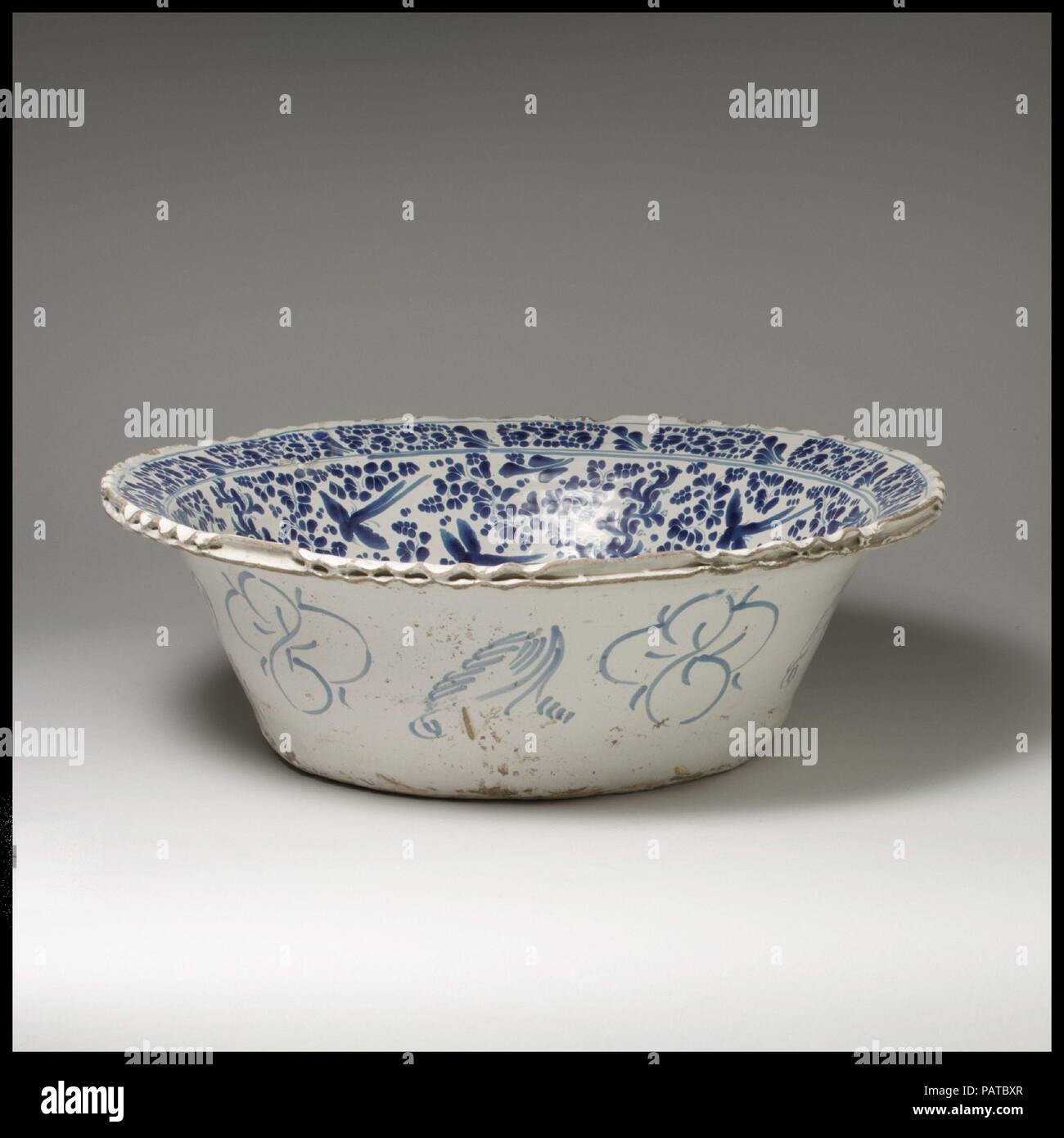 Basin. Culture: Mexican. Dimensions: H. 6 1/2 in. (16.5 cm); Diam. 20 1/4 in. (51.4 cm). Maker: Attributed to Damián Hernández (Mexican, active 1607-70). Date: 1660-80.  The shape of this type of basin, called a lebrillo, is rooted in Hispano-Islamic ceramic traditions.  In Mexico, the lebrillo was adapted to a variety of uses, both religious and domestic, often distinguishable by the way in which they are decorated. The interior of this basin, glazed in a technique called aborronado, features a woman in contemporary dress surrounded by birds and a dense pattern of dotted foliate decoration. T Stock Photo