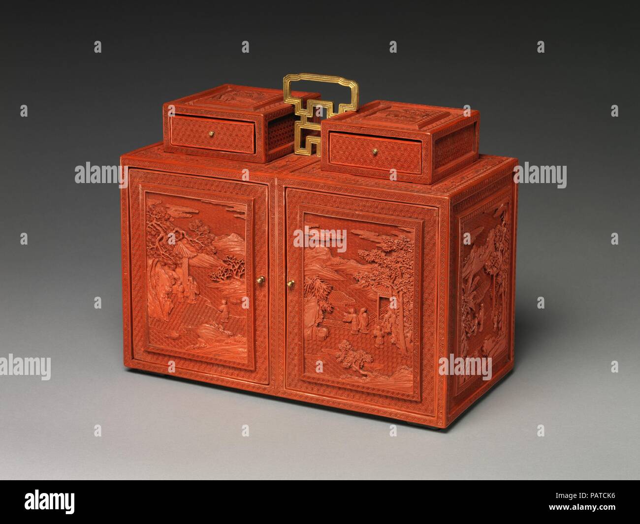 Cabinet with Figures in a Landscape. Culture: China. Dimensions: H. 13 in. (33 cm); W. 7 7/8 in. (20 cm); L. 35.9 in. (35.9 cm). Date: 18th century.  This two-door cabinet looks as if it is two separate boxes held together by the gilt-bronze handles at the top, but it is actually a single piece. The six side panels are decorated with figures along a riverbank or on a garden terrace by the water, with receding hills in the far distance. The tops of the two drawers are adorned with deer in a landscape. The sharp, precise carving of the red lacquer is characteristic of works produced in Qianlong  Stock Photo