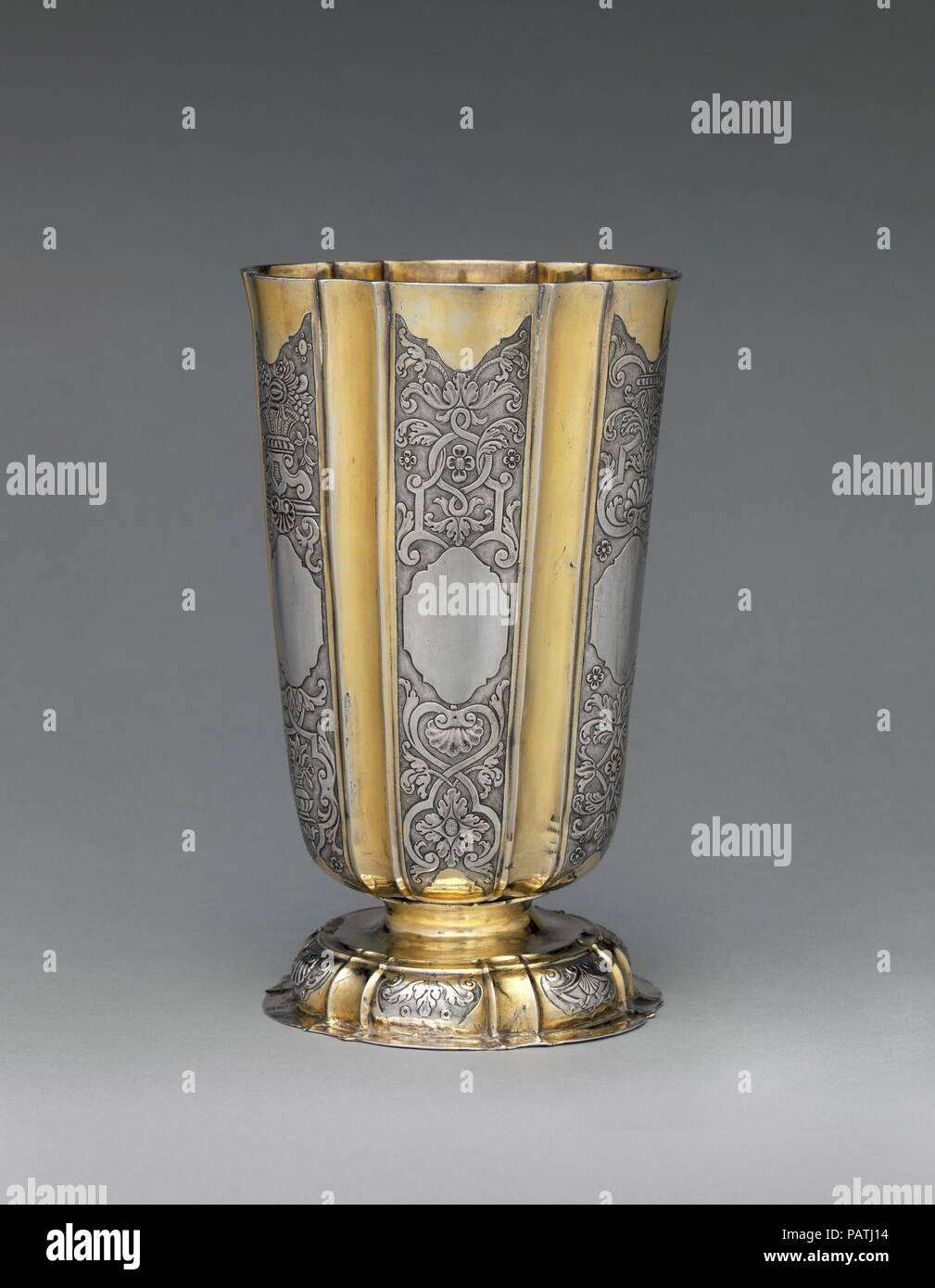 Beaker. Culture: Hungarian. Dimensions: Overall: 7 7/8 x 4 13/16 in. (20 x 12.2 cm). Maker: Georgius Olescher Jr. (master in 1721, died 1761). Date: ca. 1730-50.  An elegant rhythm is created in this beaker by alternating gilded vertical concave flutes with silver panels containing finely embossed and chased ornament on a matte ground. Georgius Olescher Jr., the maker here, was probably inspired by the work of Michael II May, who spent several years in France becoming familiar with Regence ornaments, returning to Brassó by December 1731. Other Transylvanian beakers are similarly decorated, inc Stock Photo