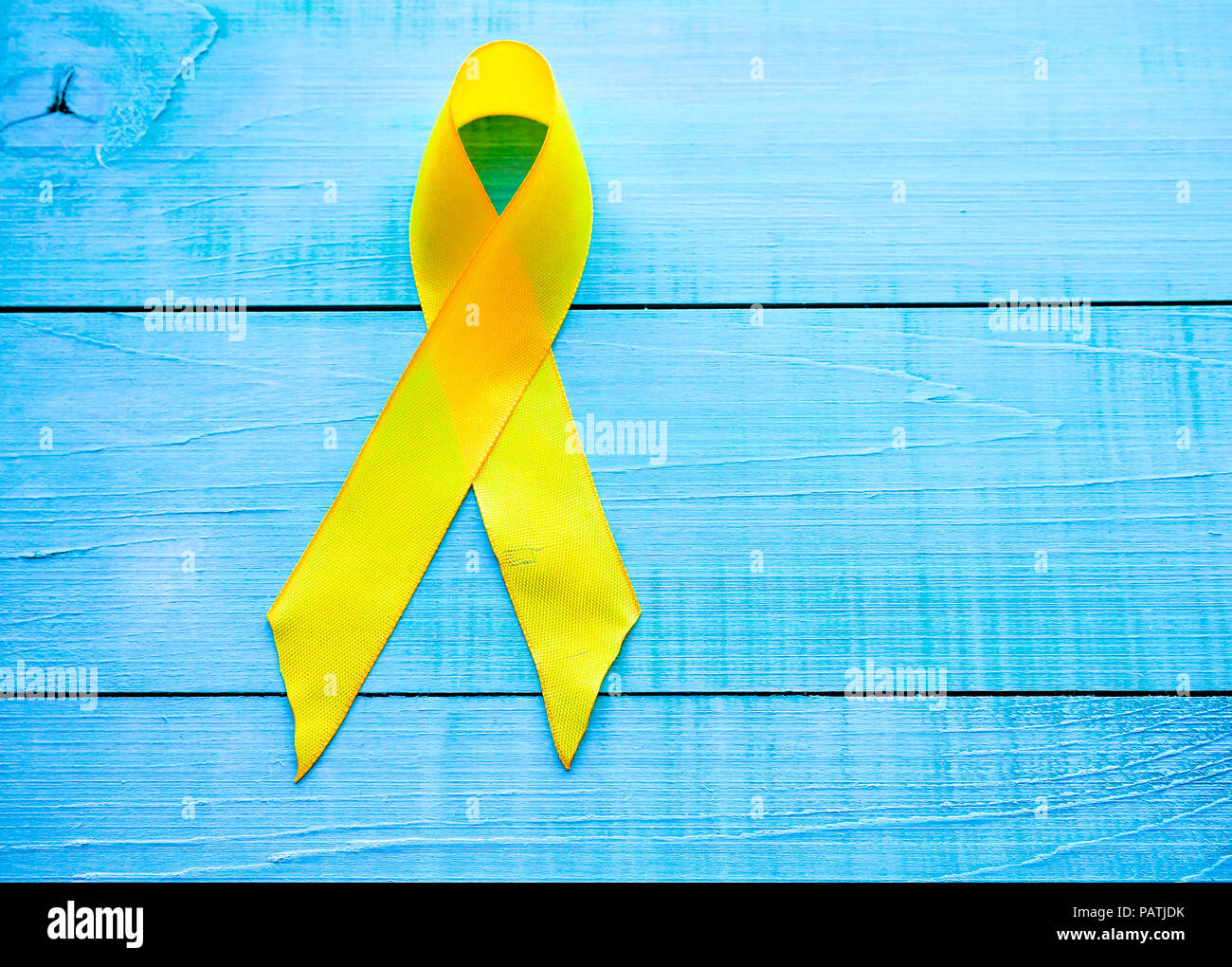 Childhood Cancer Day. Yellow Ribbon on blue background. Stock Photo