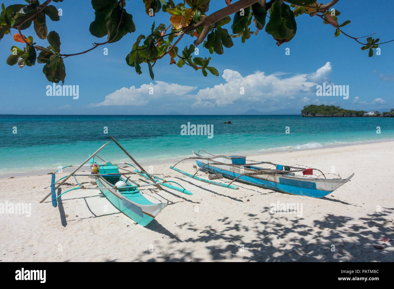 Two traditional wooden fishing boats docked on a pristine white-sand beach in north Cebu, Philippines Stock Photo