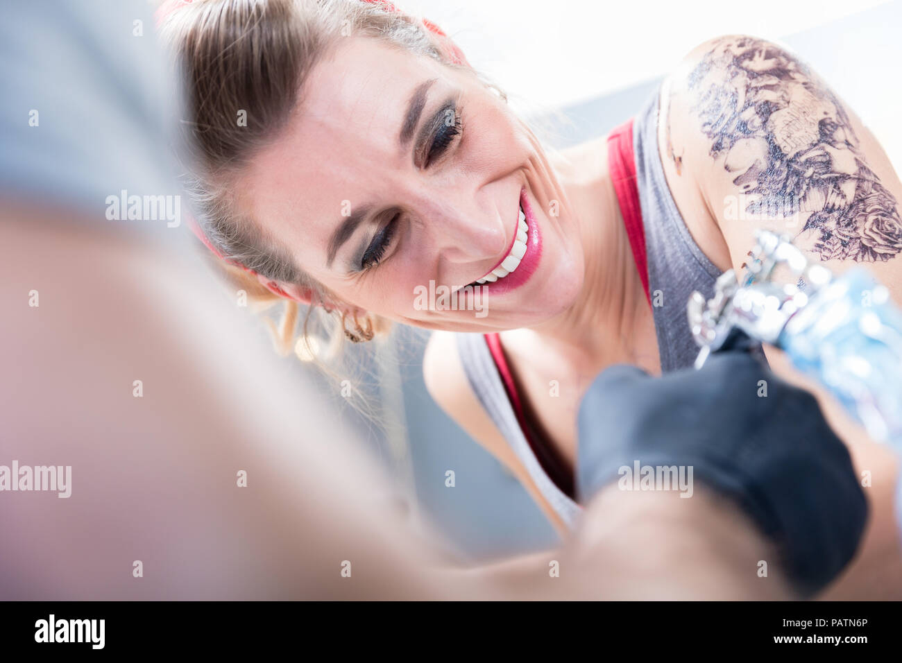 Cheerful woman smiling with confidence in a modern tattoo studio Stock Photo