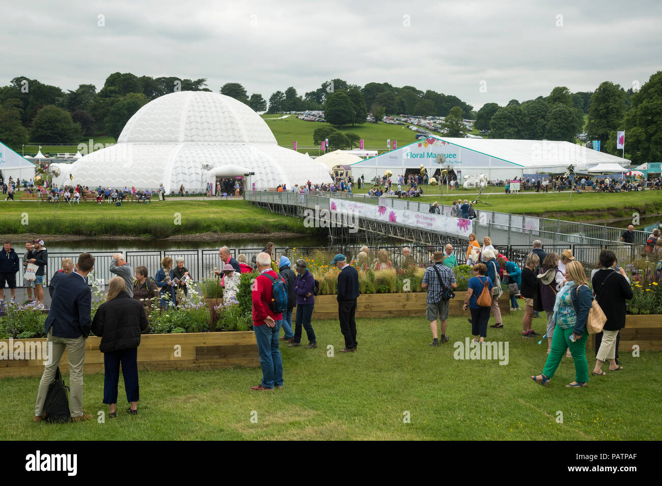 Showground at RHS Chatsworth Flower Show (visitors by exhibits, marquee, Great Conservatory dome, river & temporary bridge) Derbyshire, England, UK. Stock Photo