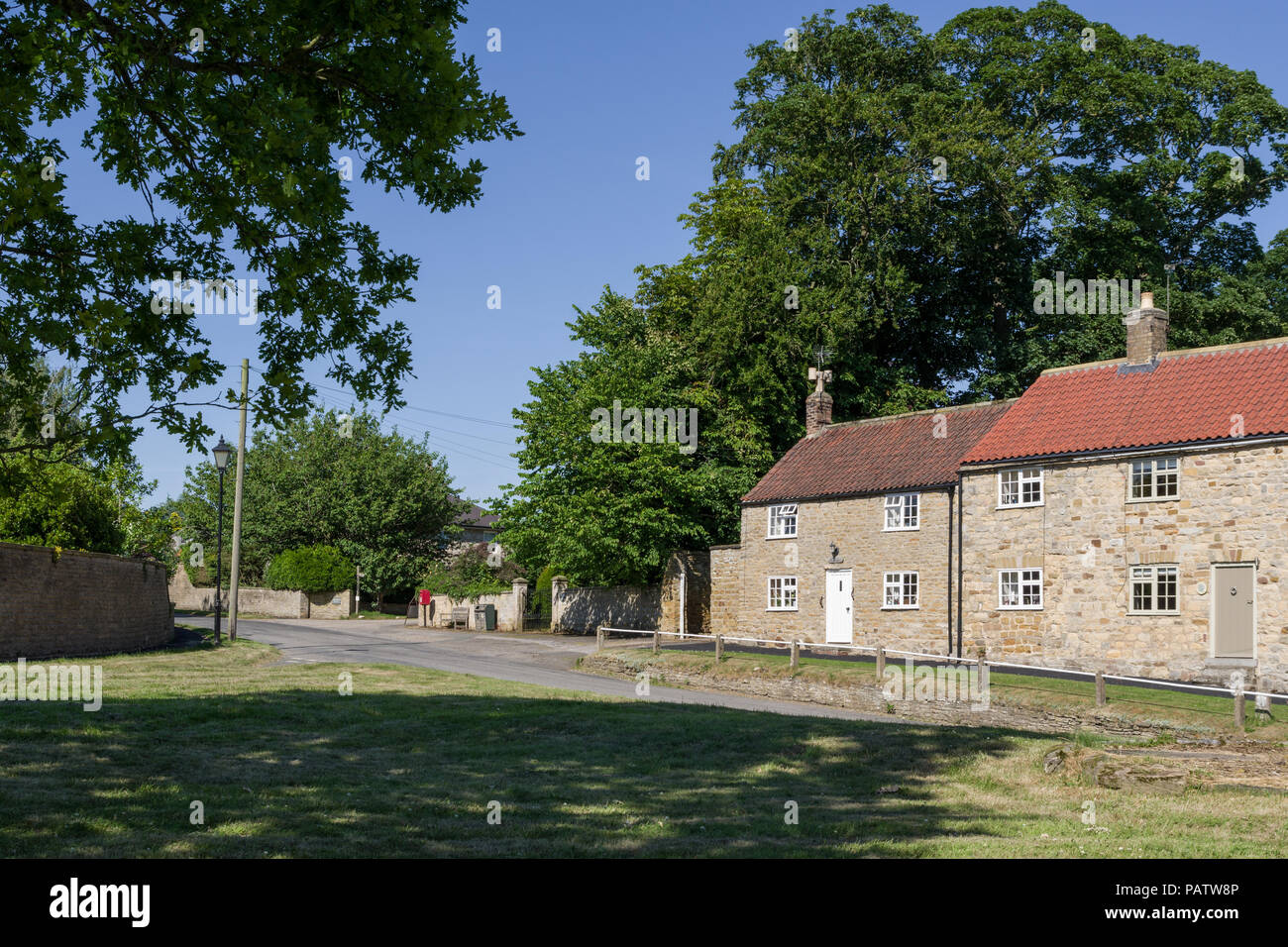 Traditional stone houses ringing the village green in the attractive and unspoilt village of Oulston, North Yorkshire, UK Stock Photo