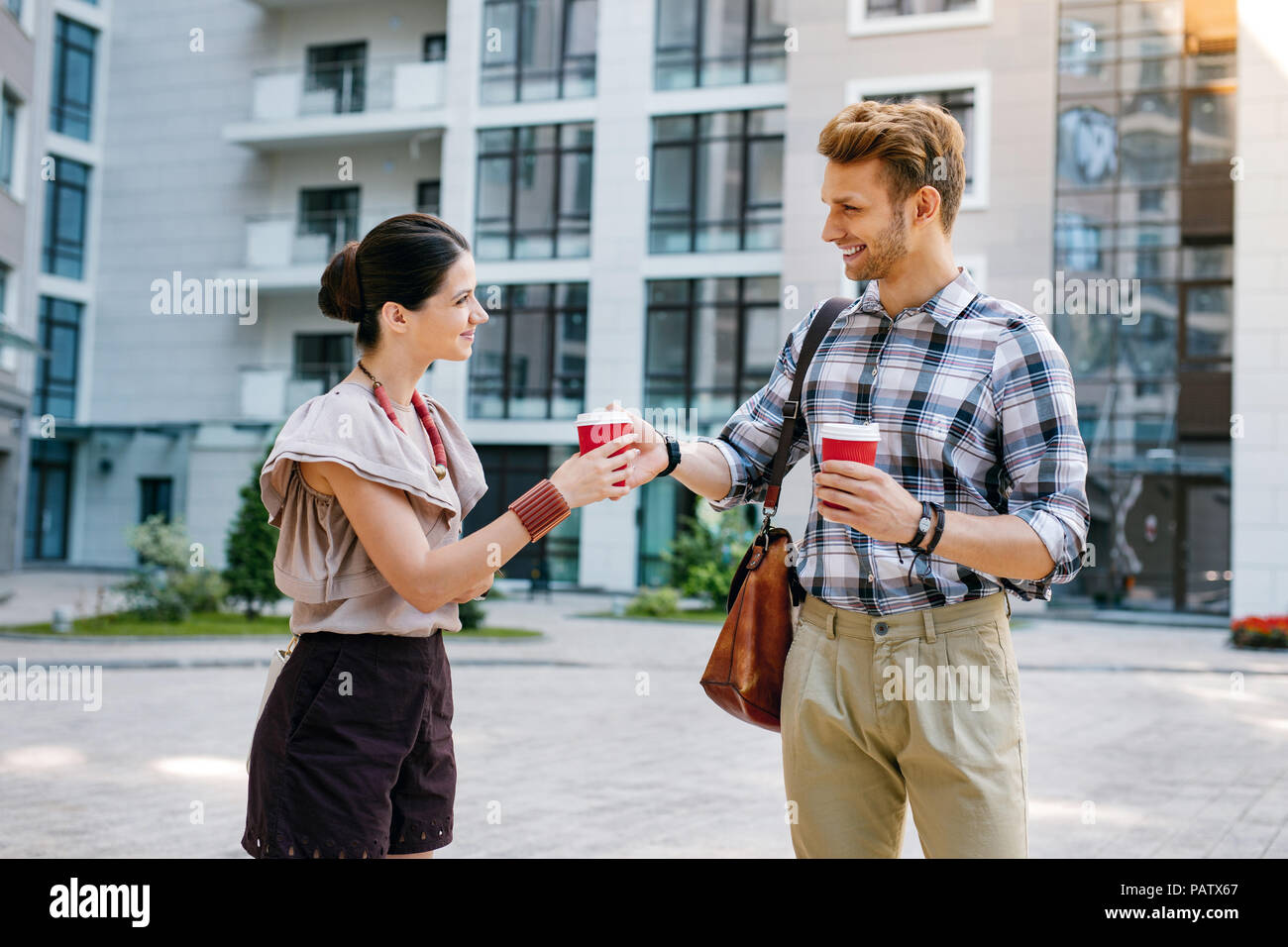 Pleasant friendly man giving a cup of coffee to his friend Stock Photo