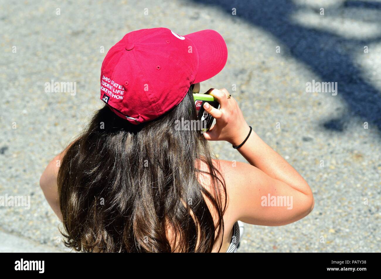 Chicago, Illinois, USA. A woman uses her cell phone while sitting on the curb waiting for the start of the Chicago Pride Parade. Stock Photo