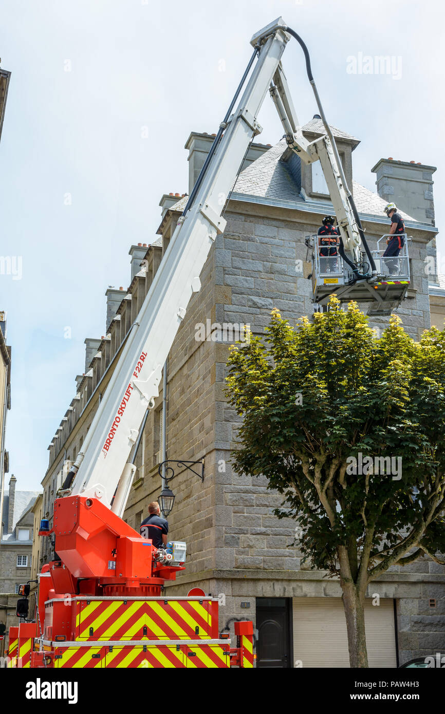 A fireman squad is practicing on an aerial platform truck to reach the upper floor of a building in the walled city of Saint-Malo, France. Stock Photo