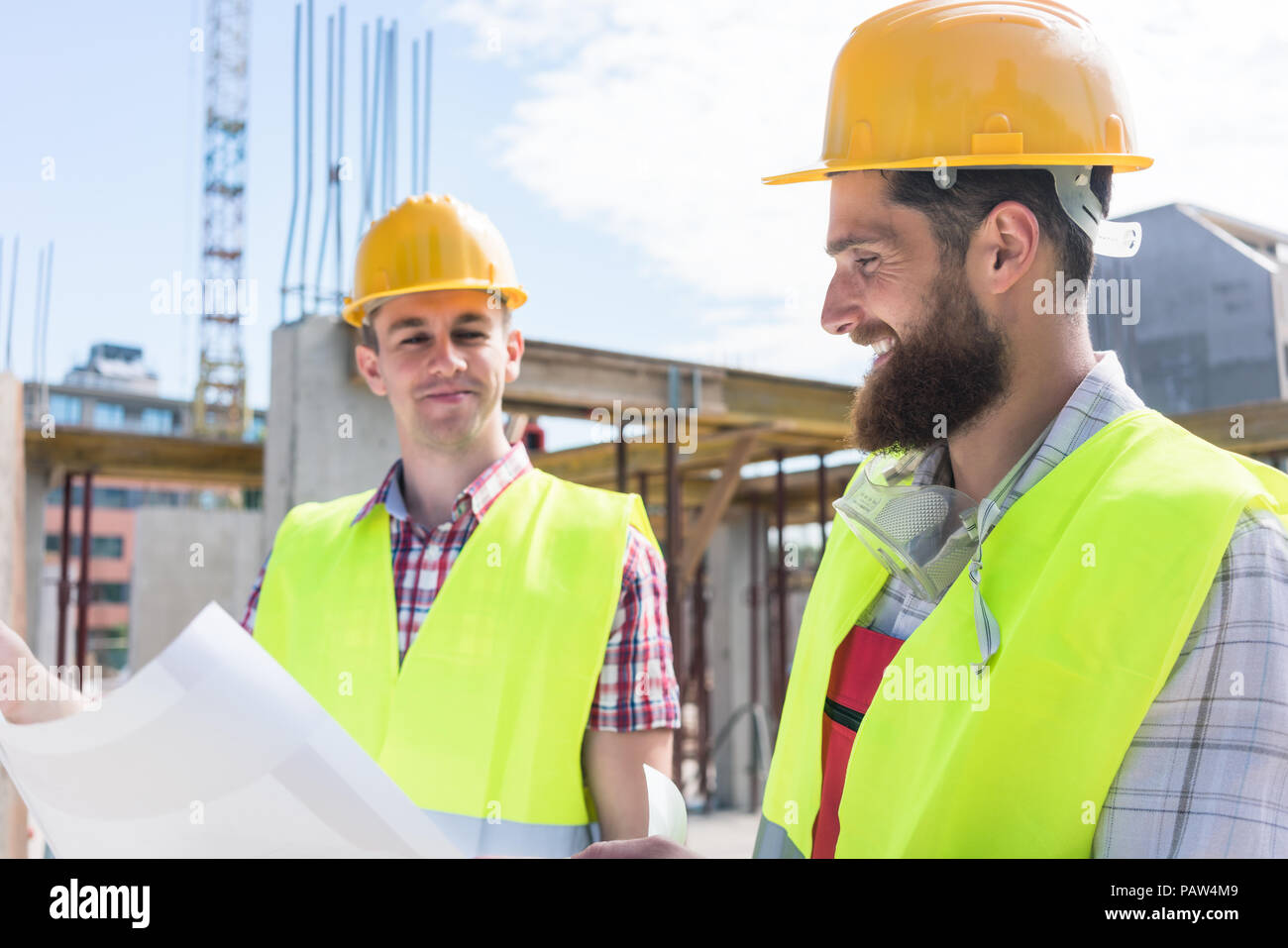 Two young construction workers analyzing together a plan Stock Photo