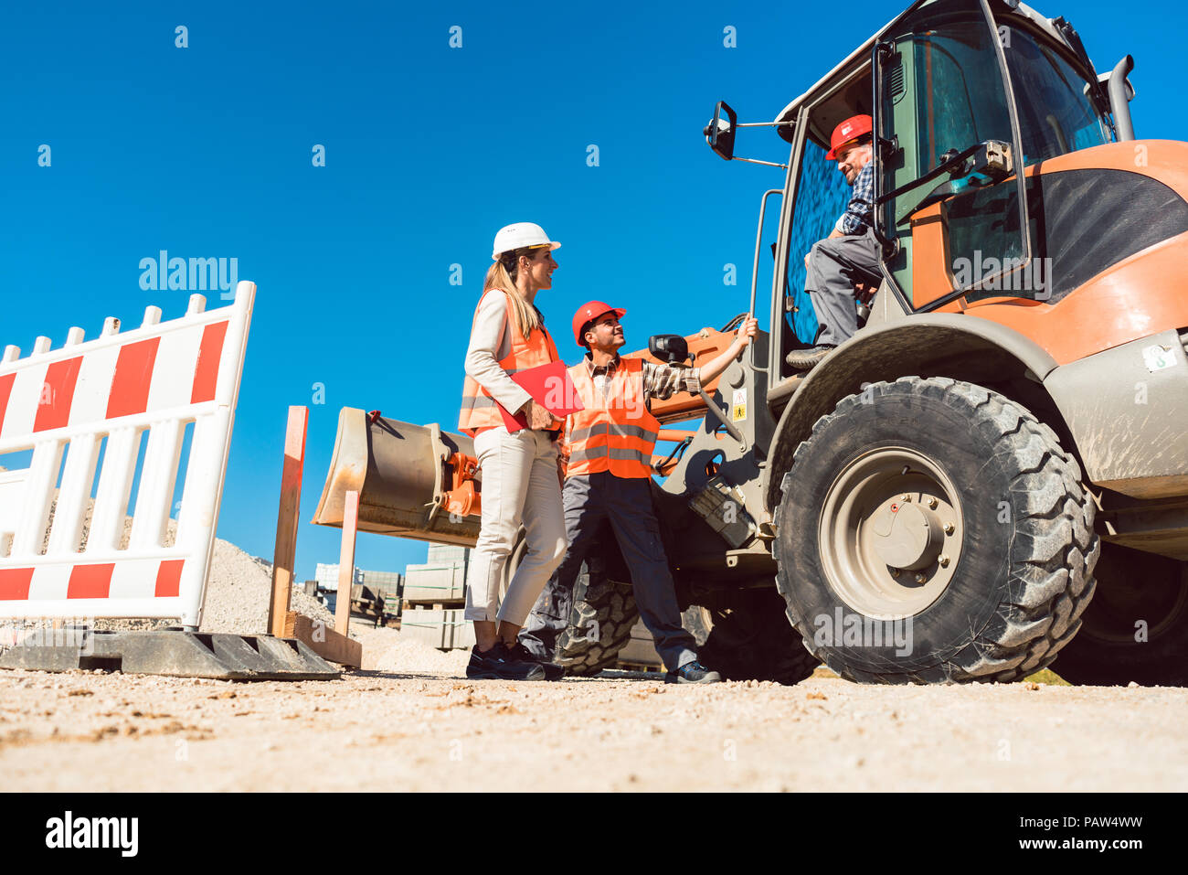 Civil engineer and worker discussion on road construction site Stock Photo
