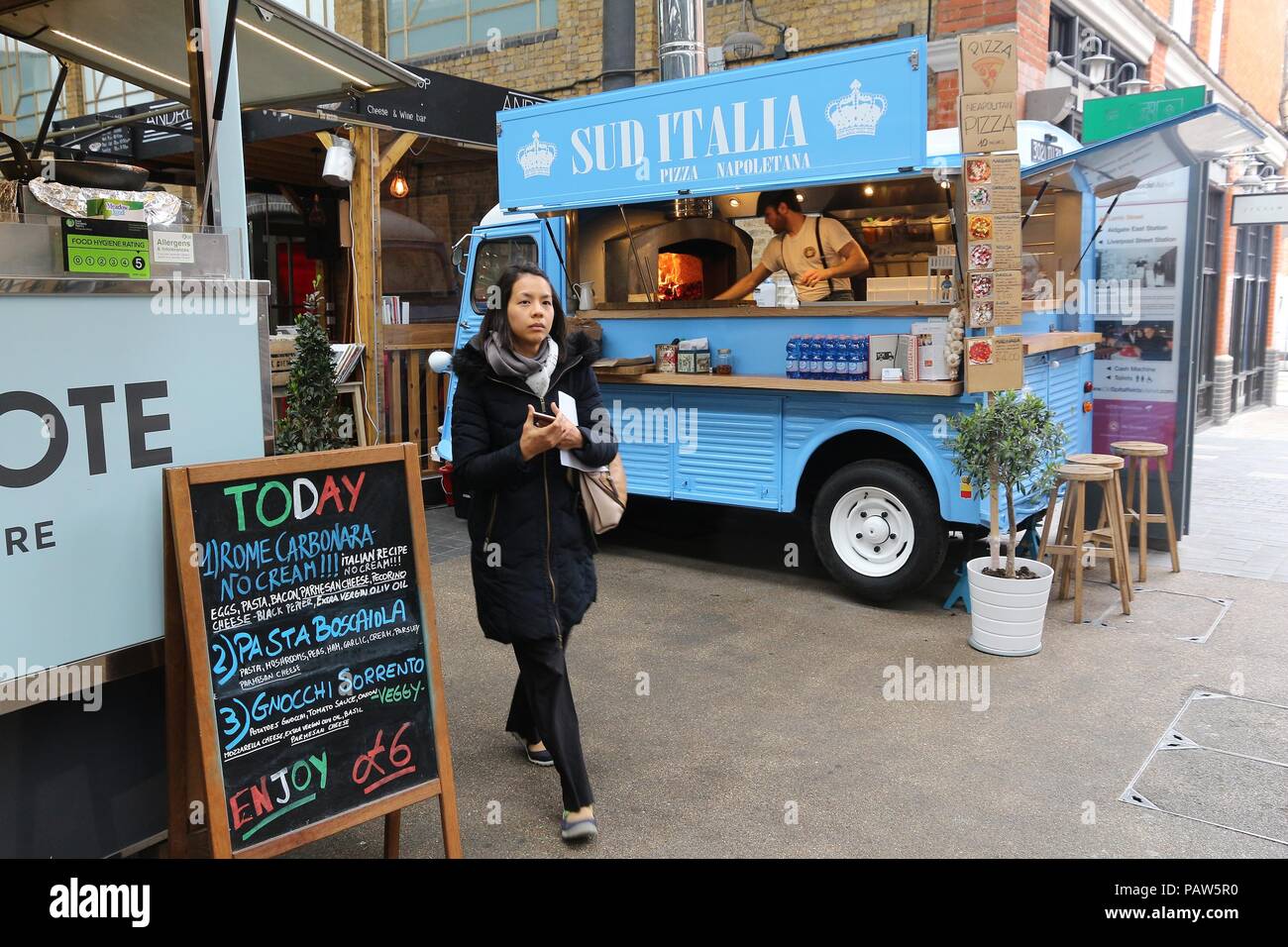 LONDON, UK - APRIL 22, 2016: People visit a pizza food truck in Old Spitalfields Market in London. A market existed here for at least 350 years. Stock Photo