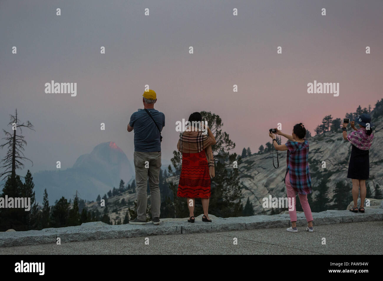 Yosemite National Park, California, USA. 24th July, 2018. Tuesday, July 24, 2018.Yosemite National Park visitors take photos at Olmsted Point along Tioga Pass Road/Highway 120 in the park's high country. Half Dome is seen in the background through the Ferguson Fire smoke. The fire is burning near the park's El Portal entrance. Credit: Tracy Barbutes/ZUMA Wire/Alamy Live News Stock Photo