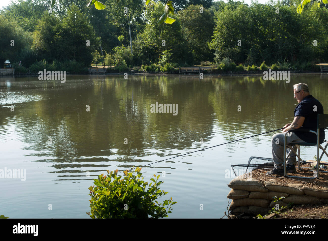 Henlow, Bedfordshire, UK, 25th July 2018. Angler Bob set up very early before the heat becomes too much for him Stock Photo
