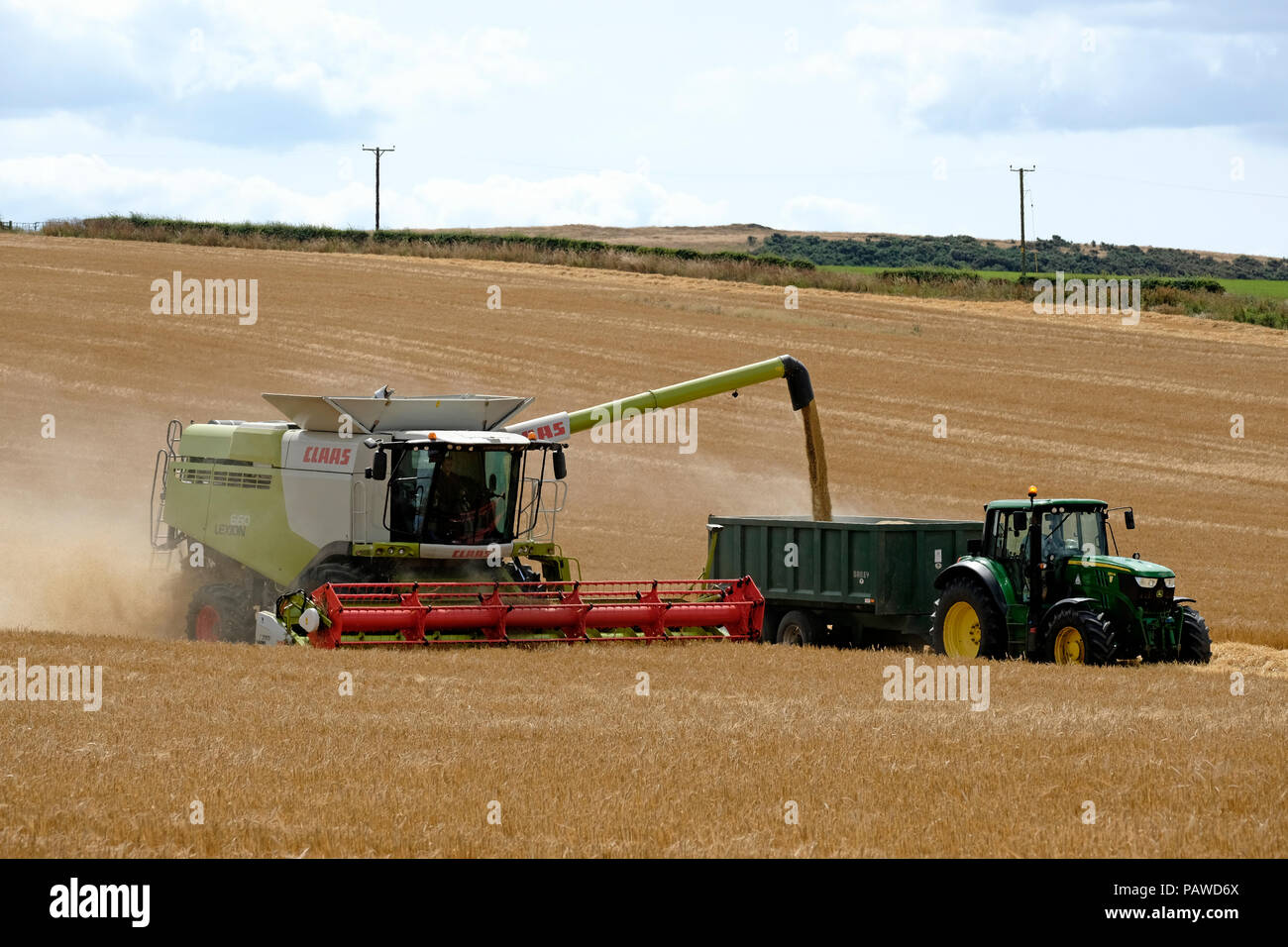 Kelso, Scotland, 25 July 2018.   Combine Harvester in Scottish Borders Tom Stewart from Sandyknowe Farm, near Kelso in the Scottish Borders, in a Claas Lexion 660 with Vario 770 cutterbar combine harvester, working in fields near his farm on Wednesday 25 July 2018. transferring crop to a waiting tractor to move to the farm a few miles away.   (Photo by Rob Gray / Freelance) Credit: Rob Gray/Alamy Live News Stock Photo