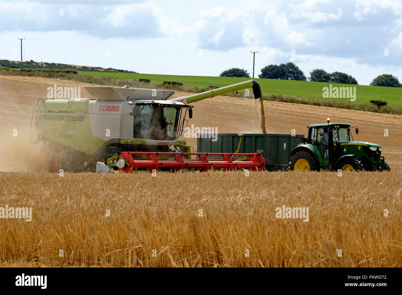 Kelso, Scotland, 25 July 2018.   Combine Harvester in Scottish Borders Tom Stewart from Sandyknowe Farm, near Kelso in the Scottish Borders, in a Claas Lexion 660 with Vario 770 cutterbar combine harvester, working in fields near his farm on Wednesday 25 July 2018. transferring crop to a waiting tractor to move to the farm a few miles away.   (Photo by Rob Gray / Freelance) Credit: Rob Gray/Alamy Live News Stock Photo