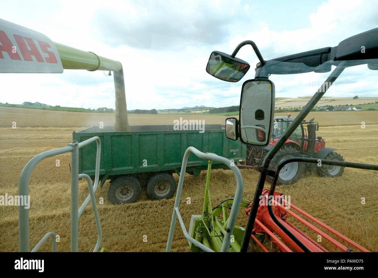 Kelso, Scotland, 25 July 2018.   Combine Harvester in Scottish Borders Tom Stewart from Sandyknowe Farm, near Kelso in the Scottish Borders, in a Claas Lexion 660 with Vario 770 cutterbar combine harvester, working in fields near his farm on Wednesday 25 July 2018. transferring crop to a waiting tractor to move to the farm a few miles away.   (Photo by Rob Gray / Freelance) Credit: Rob Gray/Alamy Live News Stock Photo