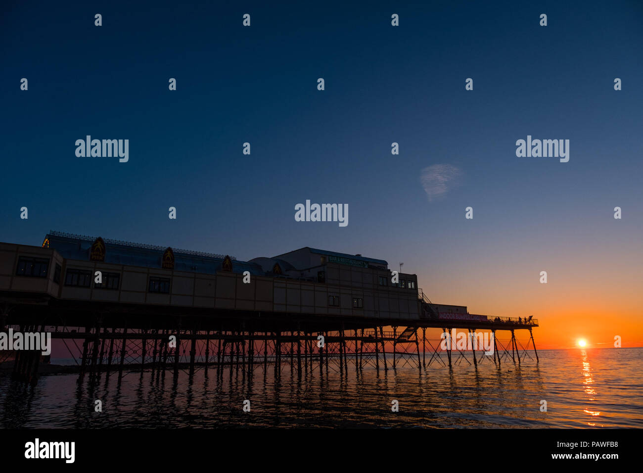 Aberystwyth Wales UK, Wednesday 25 July 2018  UK Weather: People  are silhouetted by the glorious setting sun over Aberystwyth pier at the end of a day of hot summer sunshine.  The UK wide heatwave continues, with little respite from the very dry weather  despite some rain in the forecast for the weekend  Photo credit: Keith Morris / Alamy Live News Stock Photo