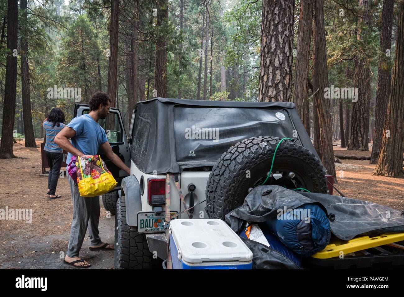 July 25, 2018 - Yosemite National Park, California, U.S - HAKIM GENTA-CLINTON, from Florida, places one of the final bags into his car as he and his friends are the last campers to depart the Upper Pines Campground in Yosemite National Park. Clinton and his two friends arrived to the park last night at 10:30pm and awoke to the news they had to leave their campsite by noon. Yosemite Valley closed to visitors at 12:00 noon Wednesday due to air quality and safety concerns with a wildfire burning near the park. Because of The Ferguson Fire, officials closed Highway 140, one of the main arteries in Stock Photo