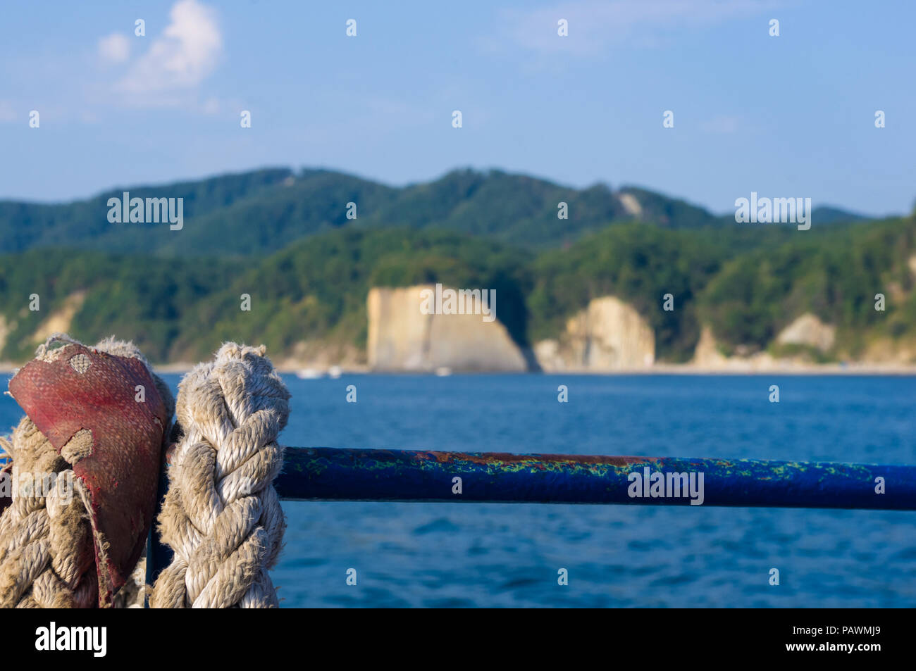 Old braided rope on the wooden deck of a sea boat, cleats, anchor mechanisms Stock Photo