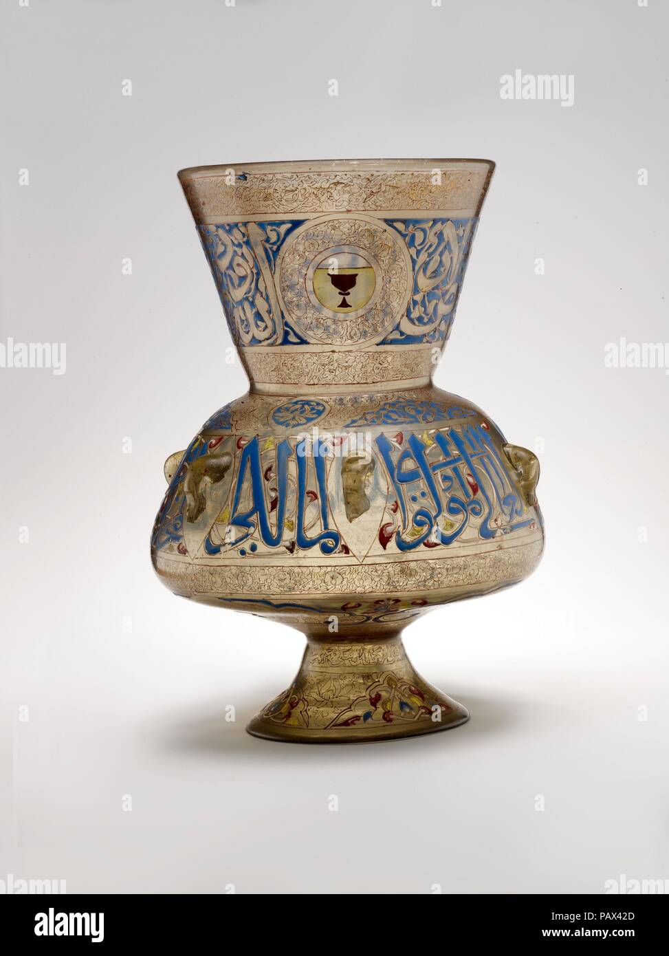 Mosque Lamp of Amir Qawsun. Dimensions: H. 14 1/8 in. (35.9 cm)  Max. diam. 10 1/16 in. (25.6 cm)  Diam. with handles 10 5/16 in. (26.2 cm). Maker: 'Ali ibn Muhammad al-Barmaki ?. Date: ca. 1329-35.  Large glass lamps of this type were commissioned by sultans and members of their court for mosques, <i>madrasa</i>s (Qur'anic schools), tombs, hospices, and other public buildings in fourteenth-century Mamluk Cairo. This example bears the name of its patron, Qawsun (d. 1342), amir of the Sultan al-Nasir Muhammad ibn Qalaun (r. 1293-1341 with brief interruptions), and was probably intended for one  Stock Photo