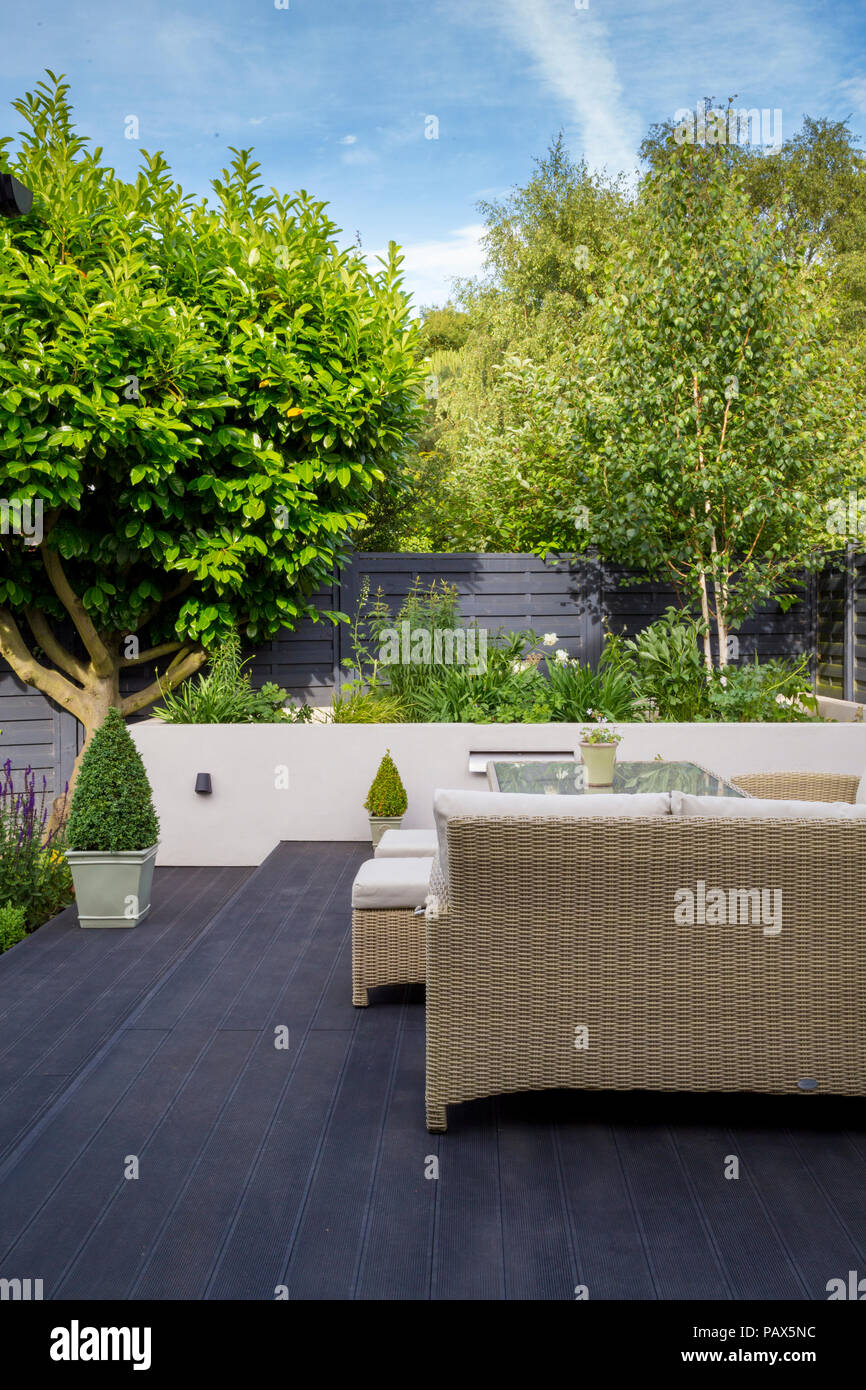 View from seating area on composite decking towards herbaceous border and Laurel tree Stock Photo