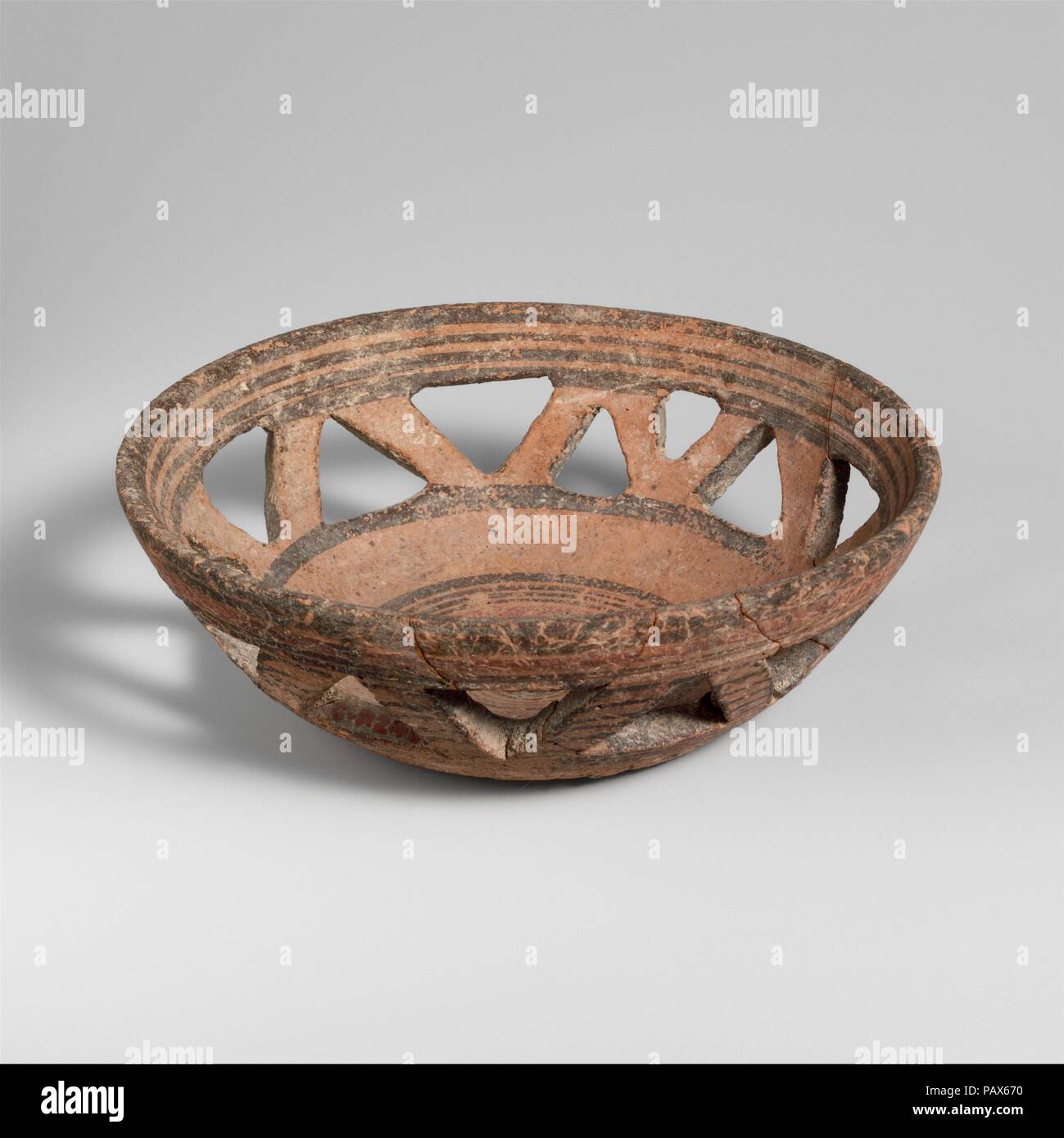 Terracotta basket bowl. Culture: Cypriot. Dimensions: H. 1 15/16 in. (4.9 cm); diameter  5 5/8 in. (14.3 cm). Date: 850-750 B.C..  Decorated with triangular openings and concentric bands in black and red. Museum: Metropolitan Museum of Art, New York, USA. Stock Photo