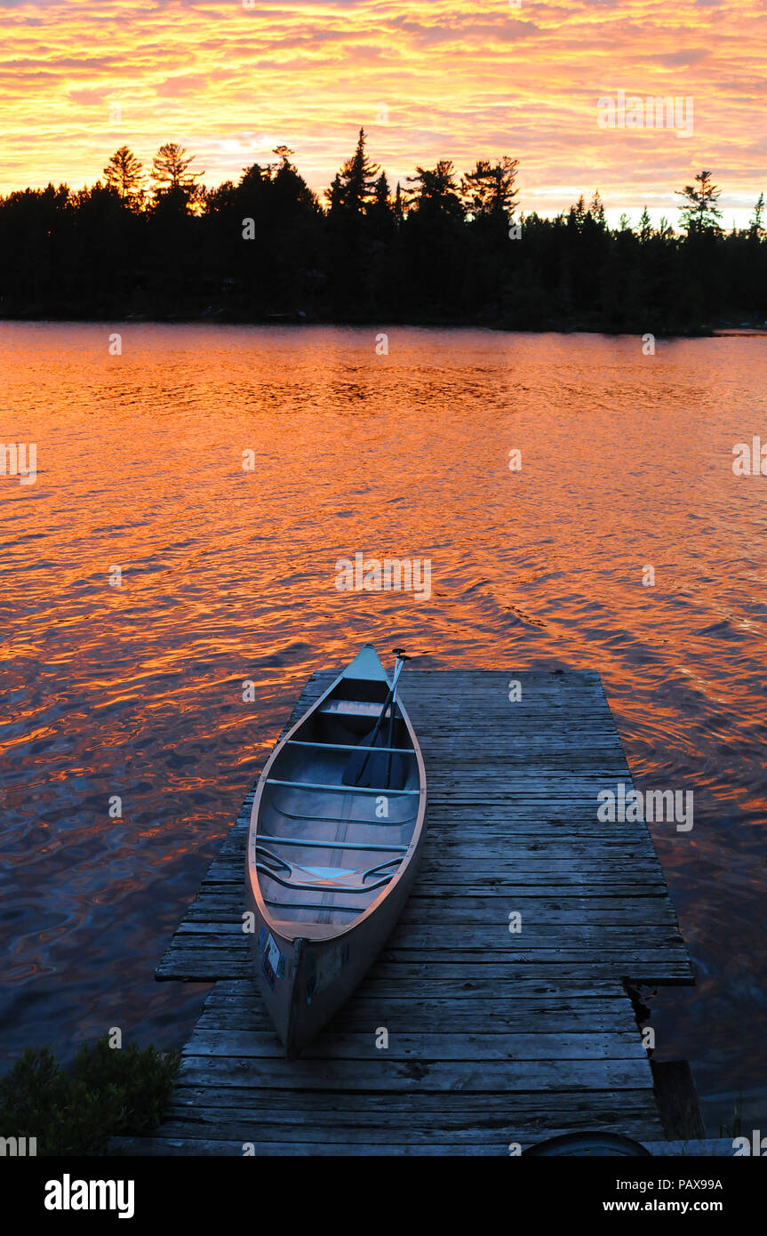 Canoe on dock at sunset sunrise on Lake One in the Boundary Waters Canoe Area near Ely Minnesota Stock Photo