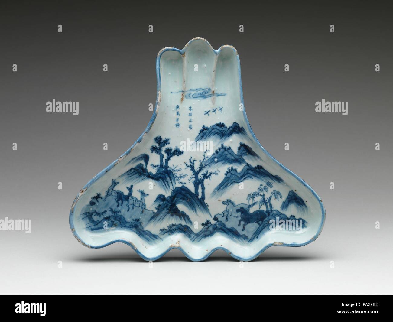 Dish in Shape of Mount Fuji with Horses and Deer. Culture: China. Dimensions: H. 2 1/16 in. (5.3 cm); W. 9 7/8 in. (25.1 cm); L. 11 1/4 in. (28.5 cm). Date: ca. 1625.  The shape of the dish, which alludes to the famed Mount Fuji, indicates that it was commissioned by a Japanese patron, most likely for a meal that accompanied the tea ceremony. The inscription, which discusses roaming with deer and horses in a landscape, is an allusion to a similar phrase in the writings of the Chinese philosopher Mencius (ca. 327-289 B.C.). Museum: Metropolitan Museum of Art, New York, USA. Stock Photo