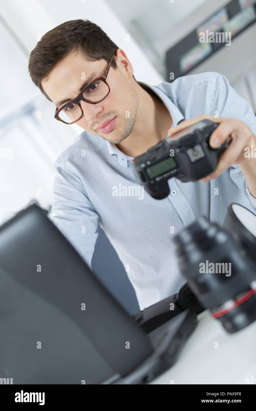 young technician working on broken camera in his office Stock Photo