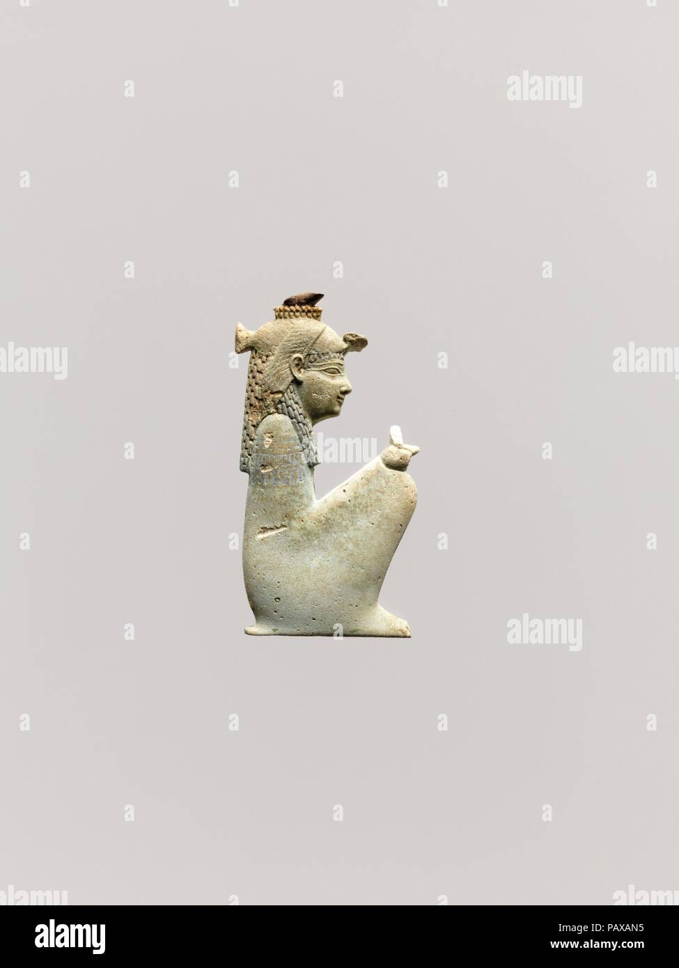 Inlay of a squatting goddess, probably Hathor. Dimensions: H. 7.1 cm (2 13/16 in.); W. 3.8 cm (1 1/2 in.); D. 1.5 cm (9/16 in.). Date: 4th century B.C..  This inlay represents a small crouching female goddess. She wears the vulture headdress associated by this time with great mother goddesses, topped by a modius of uraei and a disk, all broken away. She originally held a scepter in the fist on her knee. The king Nectanebo II incorporated into his royal names epithets relating him to the goddess Hathor. Museum: Metropolitan Museum of Art, New York, USA. Stock Photo