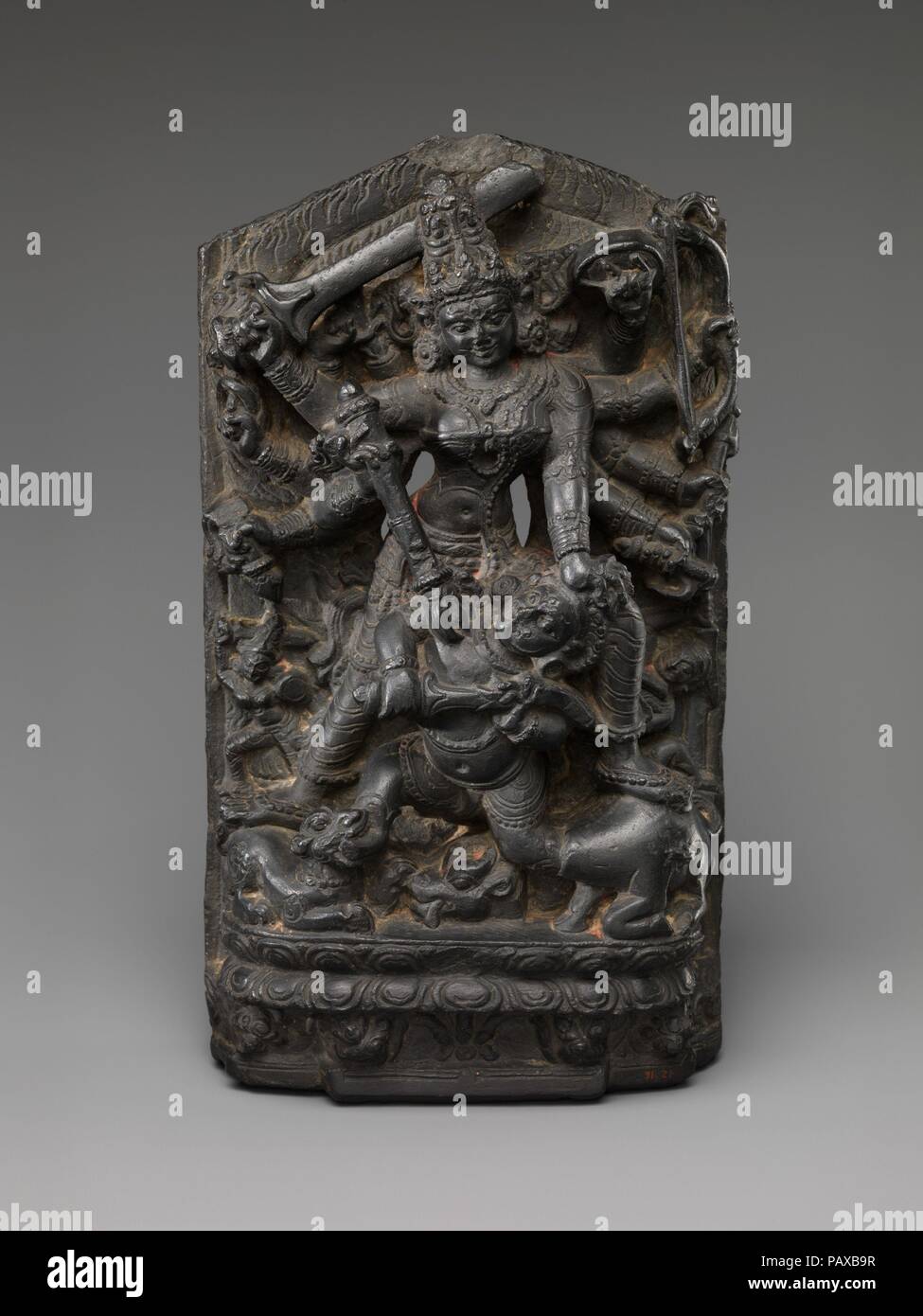 The Goddess Durga Slaying the Buffalo Demon(Mahishasura Mardini). Culture: India (Bihar). Dimensions: H. 11 1/2 in. (29.2 cm); W. 6 1/2 in. (16.5 cm); D. 3 1/2 in. (8.9 cm). Date: ca. 11th century.  Durga slays Mahisha, who emerges in his anthropomorphic form, one foot still in the neck of the decapitated buffalo and the other in the mouth of Durga's lion. Her army of followers is suggested by the small sword-wielding female warriors that bracket her feet. Museum: Metropolitan Museum of Art, New York, USA. Stock Photo