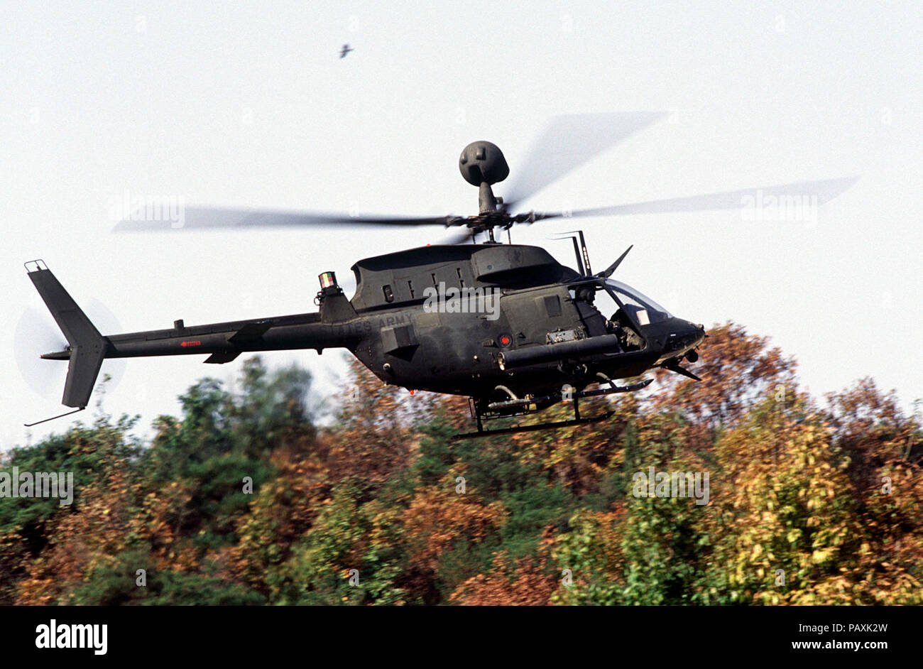 A US Army OH-58D helicopter with the 4th Squadron, 7th Cavalry Regiment hovers over the tree tops as it prepares to support armor belonging to C Troop of the 4-7 Cavalry during maneuvers and gunnery training at t(-2. A US Army  OH-58D helicopter with the 4th Squadron, 7th  Cavalry Regiment hovers over the tree tops as it prepares to support armor belonging to C Troop of the 4-7 Cavalry during maneuvers and gunnery training at the Korea Training Center, Republic of Korea on Oct. 25, 1998.  The center is manned throughout the year and various armored units rotate through training scenarios to me Stock Photo