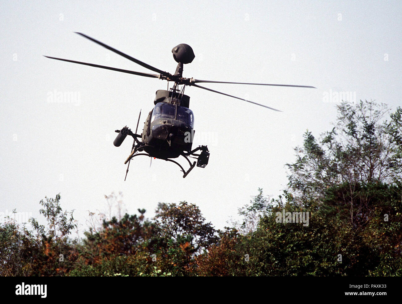 A US Army OH-58D helicopter with the 4th Squadron, 7th Cavalry Regiment hovers over the tree tops as it prepares to support armor belonging to C Troop of the 4-7 Cavalry during maneuvers and gunnery training at t(-3. A US Army OH-58D helicopter with the 4th Squadron, 7th  Cavalry Regiment hovers over the tree tops as it prepares to support armor belonging to C Troop of the 4-7 Cavalry during maneuvers and gunnery training at the Korea Training Center, Republic of Korea on Oct. 25, 1998.  The center is manned throughout the year and various armored units rotate through training scenarios to mee Stock Photo